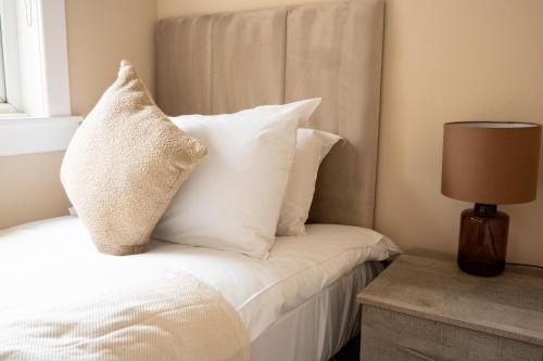 a bedroom with a bed with white pillows and a lamp at Marina House in Bathgate