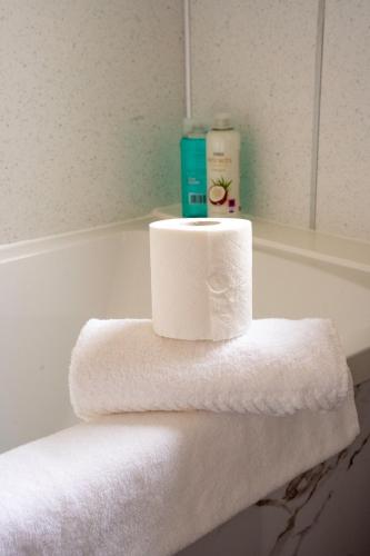 a stack of towels sitting on top of a bath tub at Marina House in Bathgate
