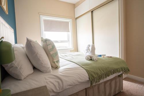 a bedroom with a bed with white pillows and a window at Marina House in Bathgate