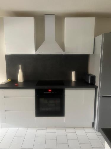 une cuisine avec des armoires blanches et un comptoir noir dans l'établissement LOCATION CAP D'AGDE, au Cap d'Agde