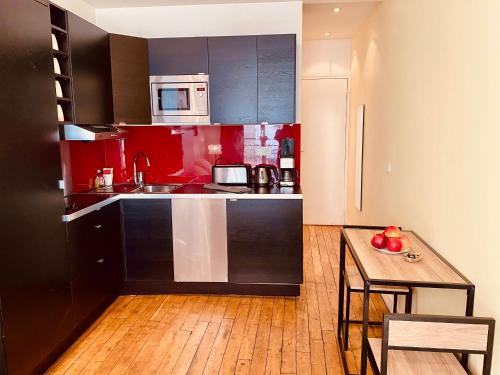 Il comprend une cuisine avec des placards rouges et du parquet. dans l'établissement Appartement Marais Cœur Historique, à Paris