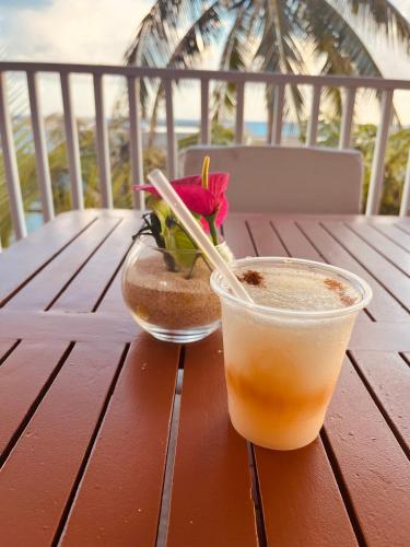 a drink and a vase with a flower on a wooden table at Lovely Seafront Apartment with Breathtaking Seaviews in Cupecoy