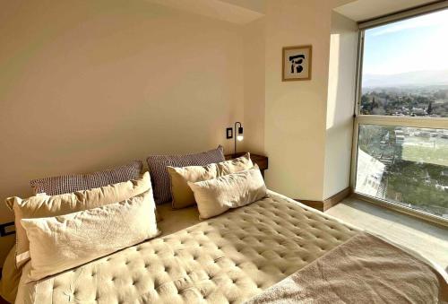 - une chambre dotée d'un lit avec des oreillers et d'une grande fenêtre dans l'établissement Departamento de lujo en el corazón de Mendoza, à Villa Marini