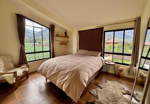 a bedroom with a bed and two windows and a rug at Bright Riverside 3 Bedroom Stay Garden 5 min to Pisac in Taray