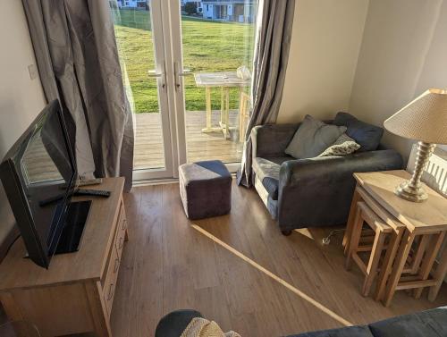 a living room with a couch and a tv in it at Saltbox B4 holiday cottage in Freshwater