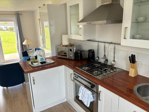 a kitchen with white cabinets and a stove top oven at Saltbox B4 holiday cottage in Freshwater