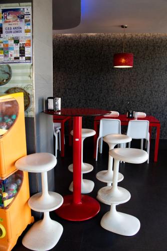 un restaurante con una mesa roja y taburetes blancos en PENSIÓN RESTAURANTE "O RETIRO ", en Arzúa