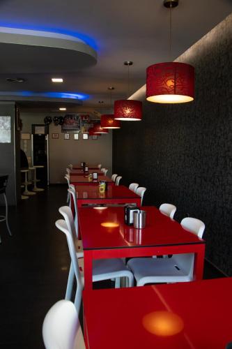 un restaurante con mesas rojas y sillas blancas en PENSIÓN RESTAURANTE "O RETIRO ", en Arzúa