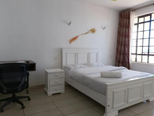 a bedroom with a bed and a desk and a chair at Lux Suites Thika Gateway Apartments in Thika