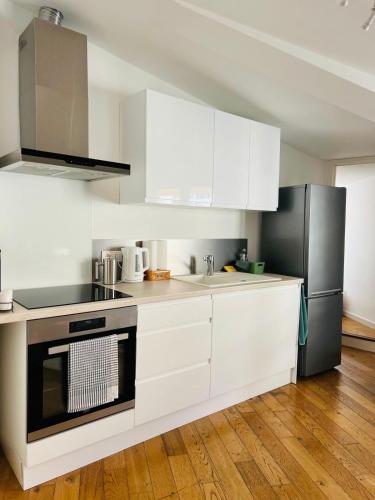 une cuisine avec des armoires blanches et un réfrigérateur noir dans l'établissement Le Chastel, T3, Aix Centre Ville, à Aix-en-Provence