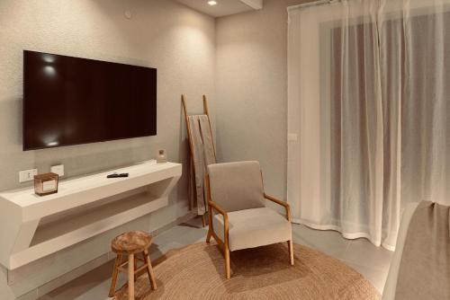 a living room with a chair and a television on a wall at Palermo Inn Boutique Hotel in Palermo