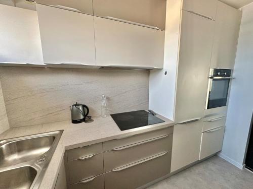 une cuisine avec des armoires blanches et un évier dans l'établissement Vue panoramique au 8ème étage avec 3 Terrasses & 1 Parking à Berck-Plage, à Berck-sur-Mer