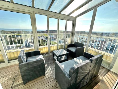ein großer Raum mit zwei Stühlen und einem Tisch und Fenstern in der Unterkunft Vue panoramique au 8ème étage avec 3 Terrasses & 1 Parking à Berck-Plage in Berck-sur-Mer