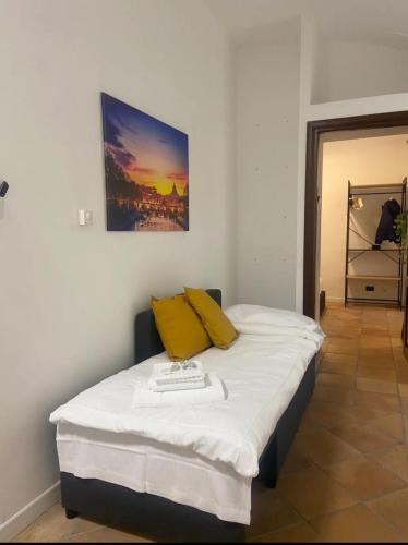 a bedroom with a bed with white sheets and yellow pillows at Cozy Colosseo in Rome