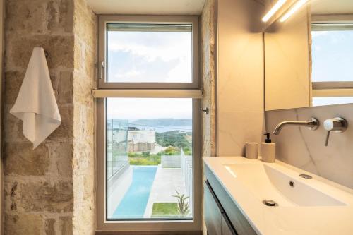 a bathroom with a sink and a window with a view at Fantasea Villas, villa Lumi in Stérnai