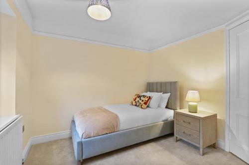 ein Schlafzimmer mit einem Bett und einem Nachttisch mit einer Lampe in der Unterkunft Daisy Cottage - North East Escapes in Corbridge