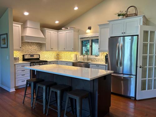 a kitchen with white cabinets and a large island with bar stools at Whitefish Home, 3 BED 2 BATH, Sleeps 7, Hot Tub, AC in Whitefish