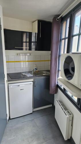 une petite cuisine avec un évier et un micro-ondes dans l'établissement Le Carrel, à Rouen