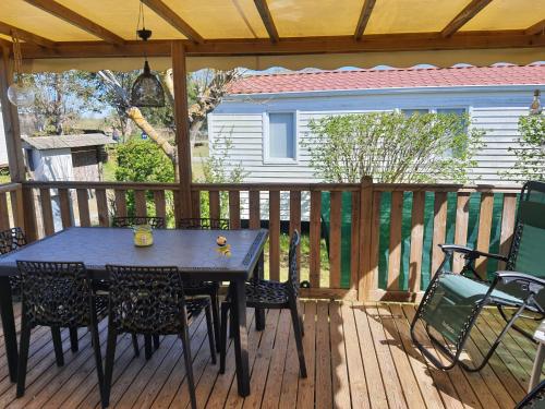 une terrasse en bois avec une table et des chaises dessus dans l'établissement Mobilhome, à LʼAmélie