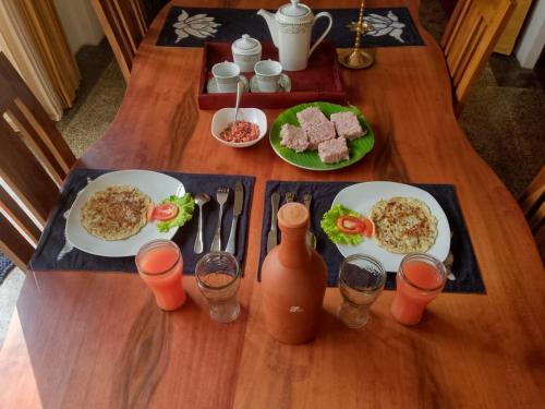 a wooden table with plates of breakfast food and drinks at Nivartana Villa and Purana Ayurveda Center in Bentota