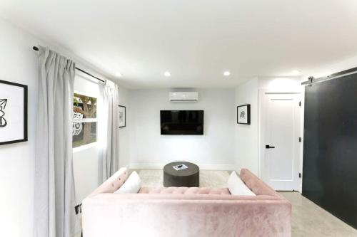 a living room with a pink couch and a table at 1BD 1BA-Black&White ArtBNB Cottage-Antique Row WPB in West Palm Beach