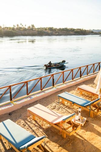 a boat in the water with lounge chairs and a boat at Fenti Nubian Resort in Aswan