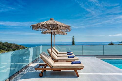 a pair of lounge chairs with an umbrella and a swimming pool at Jasmina Villas in Agios Nikolaos