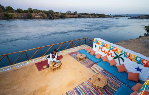 a man and a dog sitting on the side of a river at Fenti Nubian Resort in Aswan