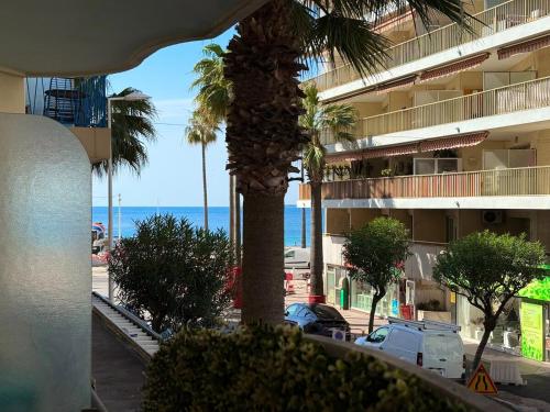 un palmier en face d'un bâtiment avec l'océan dans l'établissement Hypercentre - Vue Mer - Plage 50m, à Antibes