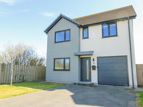 a white house with a blue garage door at 6 Gwel Yr Wyddfa in Rhosneigr