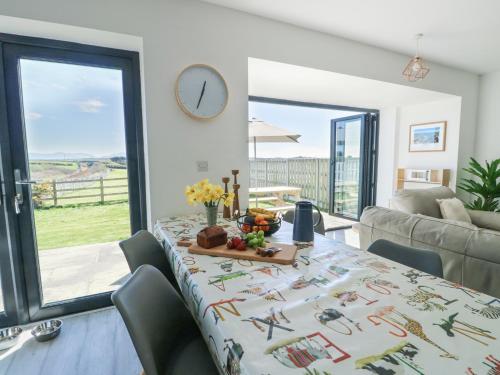 a dining room with a table and a clock on the wall at 6 Gwel Yr Wyddfa in Rhosneigr