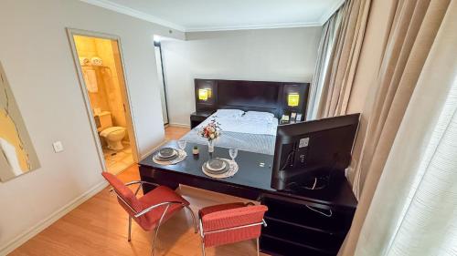 a bedroom with a bed and a desk with a television at HOTEL PERDIZES - FLAT Executivo - 1403 in Sao Paulo