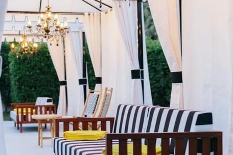 a group of chairs and tables under a marquee at Hotel El Cid by AvantStay Mid-Century Charm with Poolside Cabanas in Palm Springs