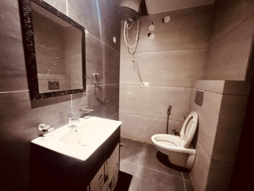 a bathroom with a sink and a toilet and a mirror at Patang Guest House in Nainital