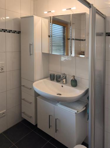 a white bathroom with a sink and a mirror at Ferienwohnung Ries am Weinberg in Platten