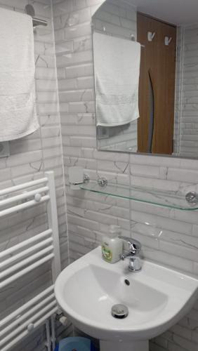 a white bathroom with a sink and a mirror at Casa Alba in Fundata
