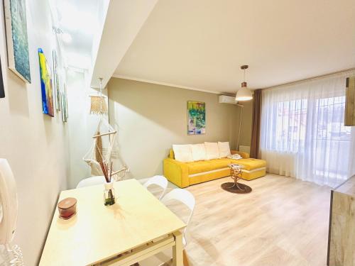 a living room with a yellow couch and a table at Apartament elegant - Cozy home residence in Piteşti