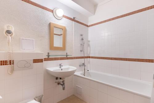 a white bathroom with a sink and a bath tub at Hotel and Park Divoká Voda in Bratislava