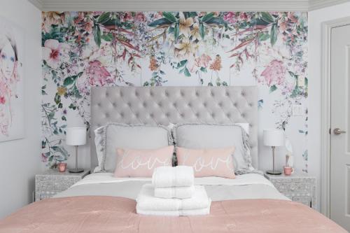 a bedroom with a large bed with pink flowers on the wall at Boutique Beach Apartment in Vancouver