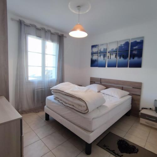 une chambre avec un lit avec des draps blancs et une fenêtre dans l'établissement Maison moderne au centre d'Oléron, à Dolus-d'Oléron