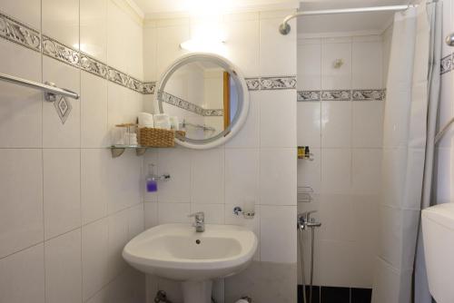 a white bathroom with a sink and a mirror at Kalokairi Apartment in Agios Nikolaos