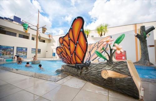 a butterfly statue in front of a swimming pool at Thermas Boulevard Suíte Hotel - Weigly in Caldas Novas