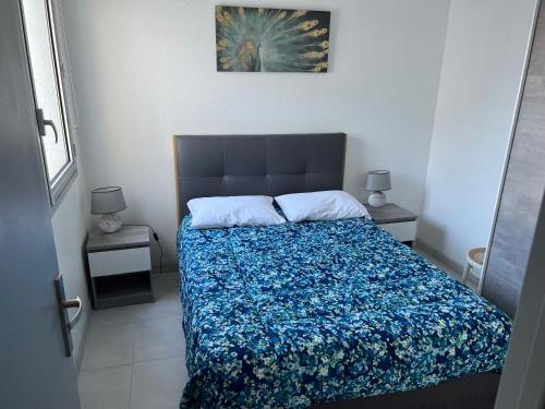 - une chambre dotée d'un lit avec un couvre-lit bleu floral dans l'établissement Résidence Estany, au Barcarès