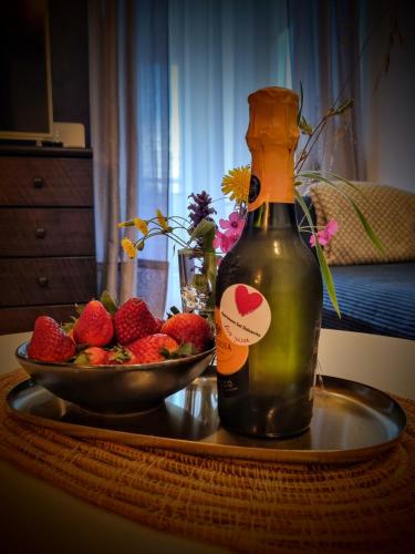 a bottle of wine on a table with a bowl of strawberries at Apartment Sol Dolcevita in Njivice