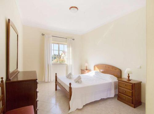 een witte slaapkamer met een bed en een raam bij Casa Camarinha in Carvoeiro