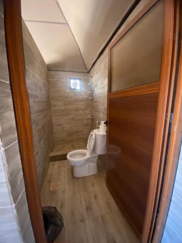 a small bathroom with a toilet and a door at wadi rum land mars in Wadi Rum