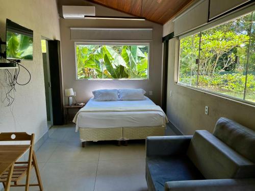a bedroom with a bed and a couch and two windows at Casa da 17 - Lago Sul in Brasília