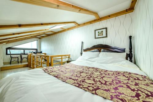 a bedroom with a bed with a red and white blanket at Jeju Hue Pension in Seogwipo