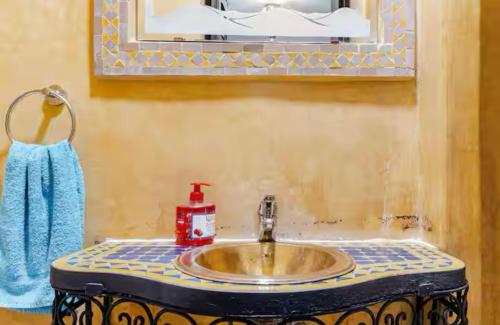 - un lavabo avec une serviette bleue et un miroir dans l'établissement Riad Zitoune, à Marrakech