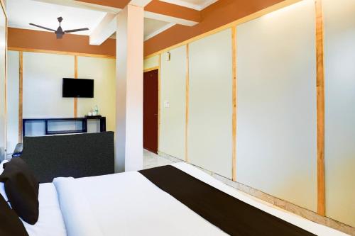 a bedroom with a white bed and a tv at Super Hotel O GMS Road Ballupur Chowk in Dehradun